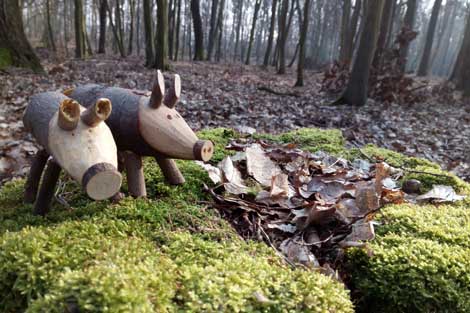 geschnitzte Wildschweine auf Moos im Wald stehend