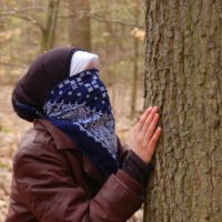 Kind mit verbundenen Augen ertastet einen Baum